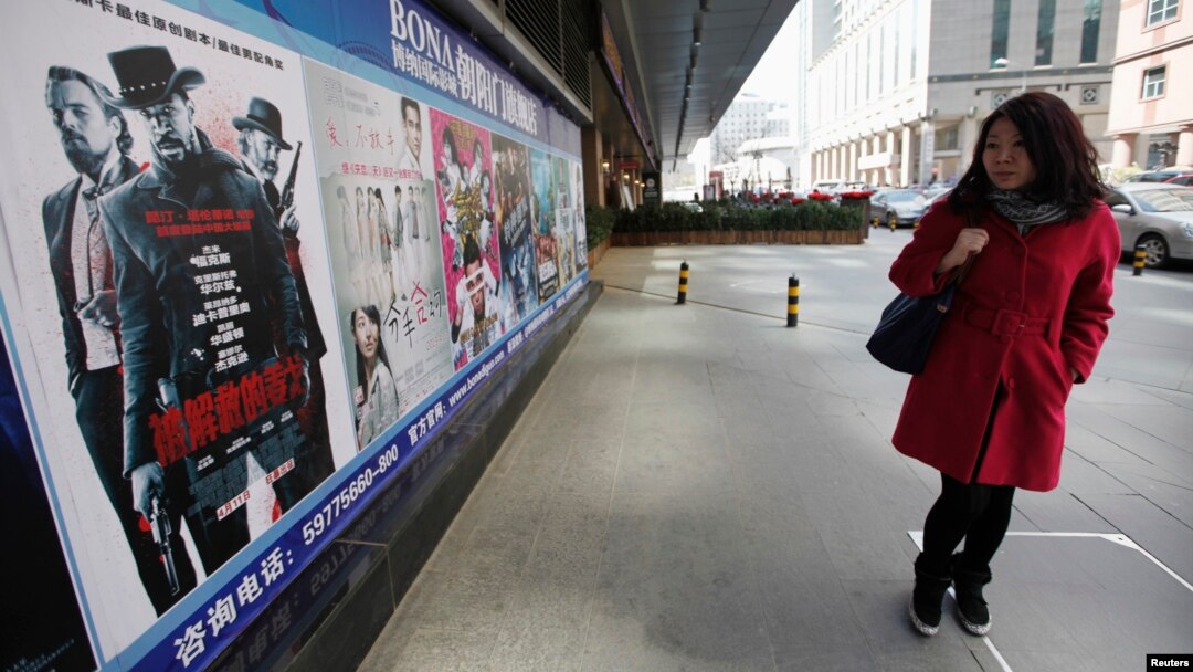 Seorang perempuan China mengamati poster film "Django Unchained" di luar bioskop di Beijing (11/4). 