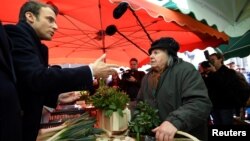 Emmanuel Macron (left), head of the political movement En Marche!, or Onward!, and candidate for the 2017 presidential election, visits a market as he campaigns in Poitiers, France, April 29, 2017.