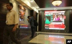 A man offers prayer to a Hindu goddess at the Bombay Stock Exchange (BSE) office, as India's Finance Minister Nirmala Sitharaman is seen on a television screen presenting the annual budget in Mumbai, India, July 5, 2019.