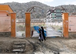 A woman with a girl walks past the site of a car bomb blast that targeted schoolgirls in Kabul, Afghanistan May 10, 2021.