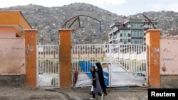 A woman with a girl walks past the site of a car bomb blast that targeted schoolgirls in Kabul, Afghanistan May 10, 2021.
