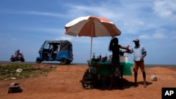 Muškarac kupuje hladno piće od prodavca pored puta po sunčanom danu u Mahawewi, selu sjeverno od Colomba, Šri Lanka, 29. februara 2024.