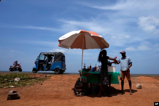 FILE - A man buys a cool drink from a roadside vendor on a sunny day in Mahawewa, a village north of Colombo, Sri Lanka, Feb. 29, 2024. (AP Photo/Eranga Jayawardena, File)