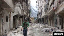 FILE photo: A Free Syrian Army fighter carries handcuffs as he walks along the rubble of damaged buildings in Aleppo's Salaheddine neighborhood, Nov. 7, 2013. 