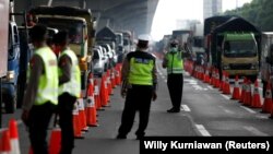 Petugas polisi mengenakan masker berjaga di pos pemeriksaan jalan raya di Bekasi, menyusul larangan mudik lebaran untuk mencegah penyebaran virus corona (COVID-19), 24 April 2020. (Foto: Willy Kurniawan/Reuters/dok) 