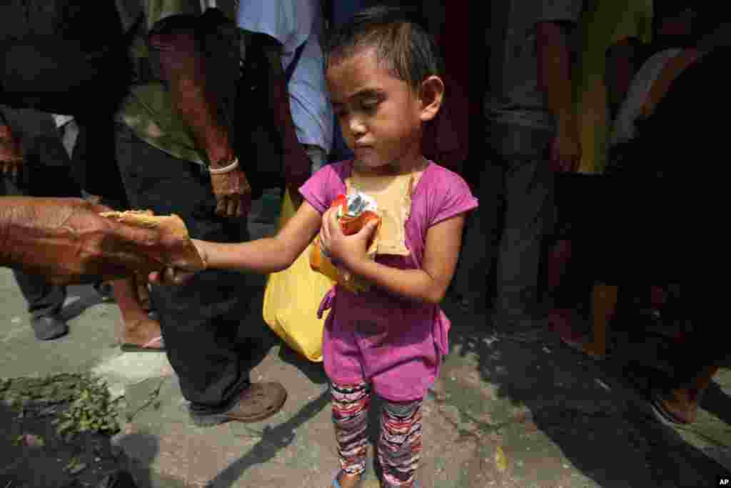 A poor Filipino girl holds bread and drinks she received during a feeding program by Dominican nuns in Manila, Philippines.