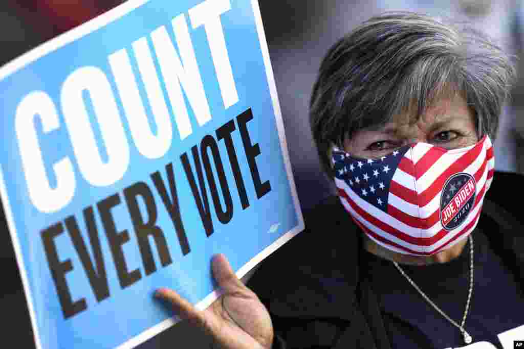 Volunteer election poll worker Cecilia Chaboudy-Dow joins demonstrators as they stand across the street from the federal courthouse in Houston, Monday, Nov. 2, 2020, before a hearing in federal court involving drive-thru ballots cast in Harris County. The