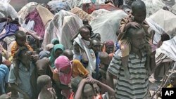 Somalis displaced by drought wait outside their makeshift shelters where tens of thousands have arrived in recent months desperately seeking food, water, shelter and other assistance, in Mogadishu, Somalia, July 25, 2011