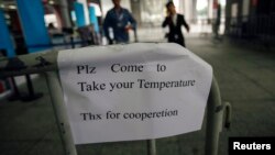 A sign requesting people to come have their temperature taken is seen at the entrance to the Canton Fair in Guangzhou, Guangdong province.