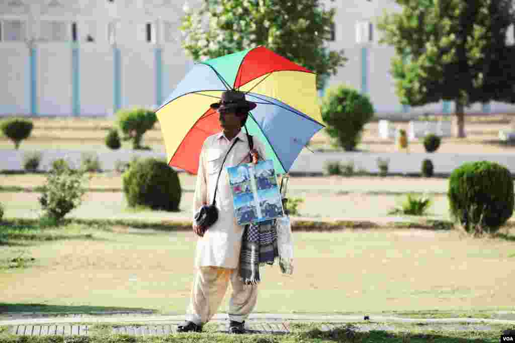 تصاویر بنانے والا ایک شخص، فیصل مسجد کے باہر انتظار میں کھڑا ہے۔