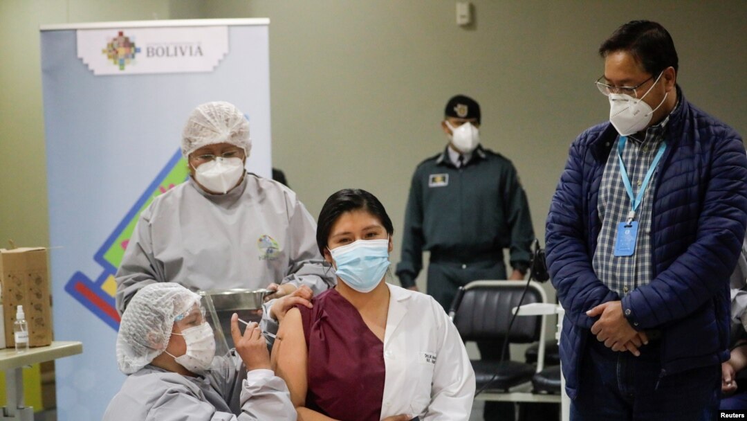 El presidente de Bolivia, Luis Arce, observa el momento en que una empleada de la salud recibe la vacuna rusa Sputnik V contra la enfermedad por coronavirus (COVID-19) en el Hospital del Norte en El Alto, afueras de La Paz, Bolivia, 30 de enero de 2021.