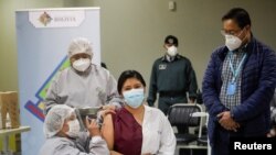 El presidente de Bolivia, Luis Arce, observa el momento en que una empleada de la salud recibe la vacuna rusa Sputnik V contra la enfermedad por coronavirus (COVID-19) en el Hospital del Norte en El Alto, afueras de La Paz, Bolivia, 30 de enero de 2021.