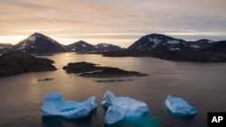 FILE - Large icebergs float away as the sun rises near Kulusuk, Greenland, Aug. 16, 2019.