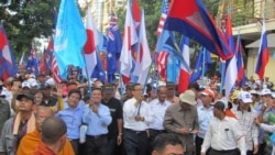 FILE - Opposition leaders Sam Rainsy and Kem Sokha hold U.N. and Cambodian flags along with their party flag while leading a march towards the U.N. office in Phnom Penh, Oct. 23, 2013. (Khoun Theara/VOA Khmer)