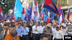 FILE - Opposition leaders Sam Rainsy and Kem Sokha hold U.N. and Cambodian flags along with their party flag while leading a march towards the U.N. office in Phnom Penh, Oct. 23, 2013. (Khoun Theara/VOA Khmer)