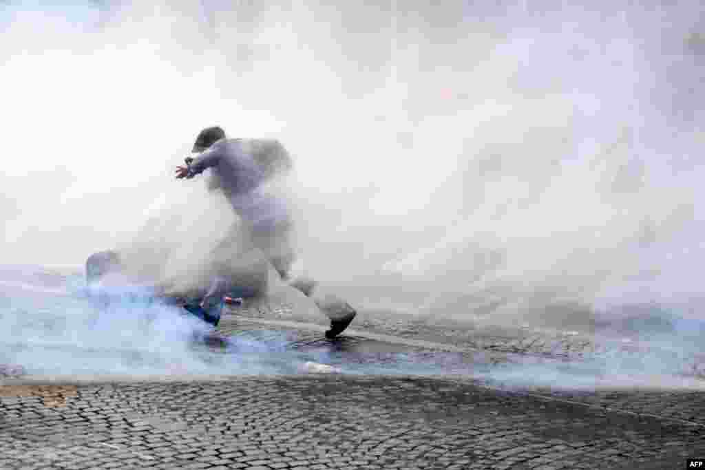 A protester runs through tear gas during a Paris demonstration against compulsory vaccination for certain workers and the use of a health pass called for by the French government, July 24, 2021.