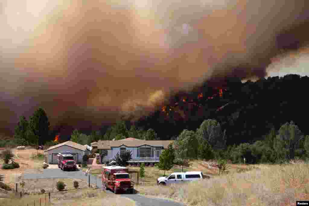 Firefighters protect an evacuated home while the fast-moving wildfire called &quot;Sand Fire&quot; burns behind, near Plymouth, California, USA, July 26, 2014.