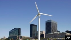 FILE - A small wind turbine rises in front of the downtown skyline at the Great Lakes Science Center in Cleveland.