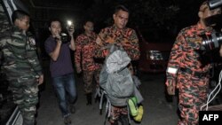 A member of a Malaysian rescue team, center, carries victims body parts inside a bag a day after the earthquake in Kundasang, a town in the district of Ranau, June 6, 2015. 