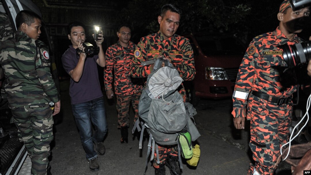 Petugas penyelamatan Malaysia (tengah) membawa bagian tubuh para korban dalam tas ransel di Kundasang, distrik Ranau, Sabau (6/6). (AFP/Mohd Rasfan)