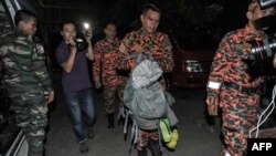 Petugas penyelamatan Malaysia (tengah) membawa bagian tubuh para korban dalam tas ransel di Kundasang, distrik Ranau, Sabau (6/6). (AFP/Mohd Rasfan)