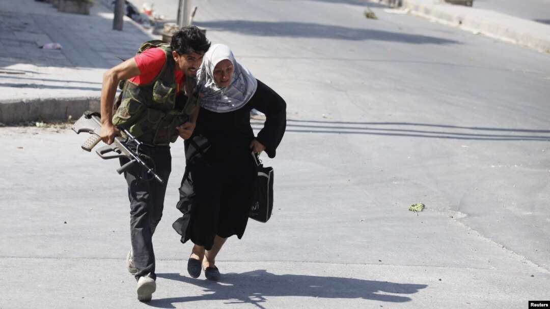 Seorang anggota Laskar Pembebasan Suriah membantu seorang perempuan menyeberang jalan di Aleppo (foto: dok). Seorang wartawan Jepang tewas saat menyertai pemberontak Suriah di Aleppo. 