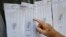 Un hombre busca su número de identificación en una lista de votantes durante un ensayo de votación en la escuela secundaria Andrés Bello en Caracas, el 10 de octubre de 2021.