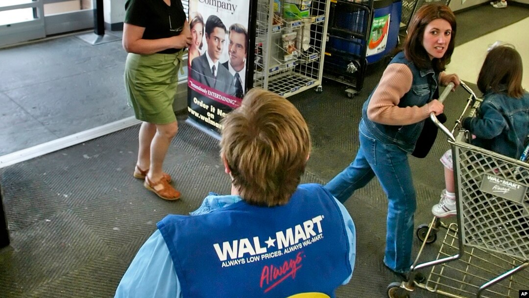 FILE - A store greeter offers help to shoppers at a Walmart store in West Norriton, Pa.