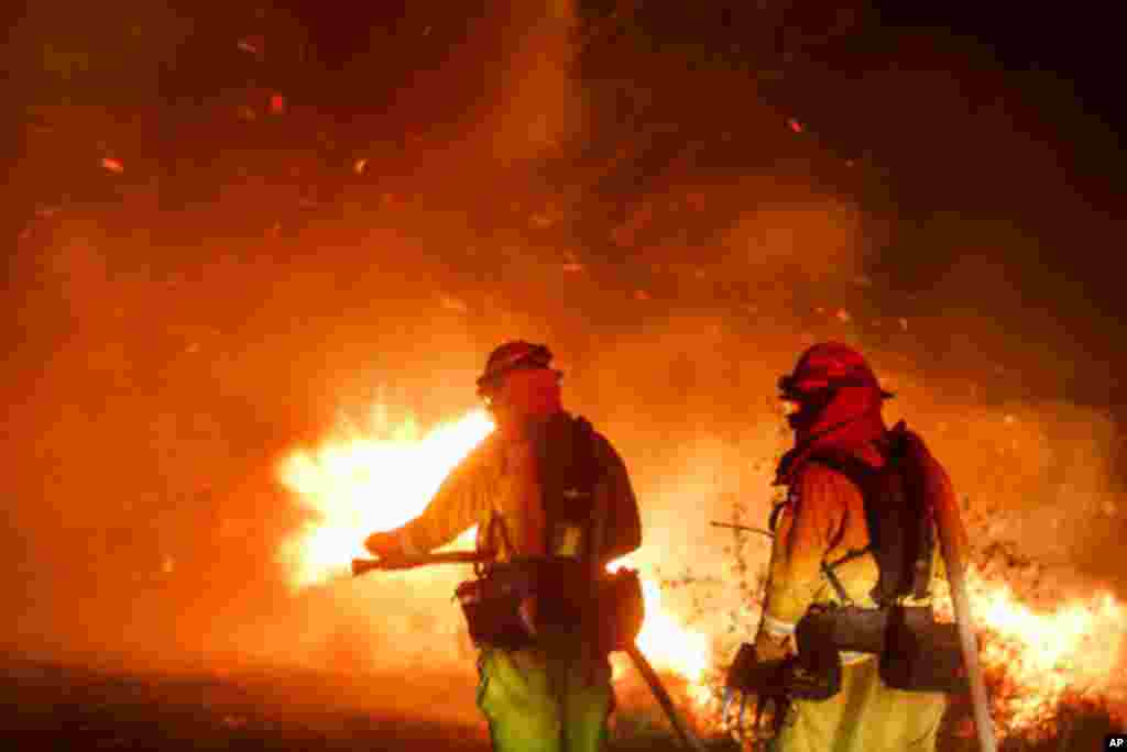 Los bomberos combaten un incendio forestal en Riverside, California, este jueves. Se espera que los vientos de Santa Ana permanezcan un último día después de conducir a más de una docena de incendios forestales a través de California.