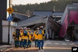 Petugas penyelamat mencari rumah-rumah runtuh yang rusak akibat gempa dahsyat di Anamizu di semenanjung Noto yang menghadap Laut Jepang, barat laut Tokyo, Kamis, 4 Januari 2024. (Foto: AP)