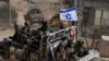 Israeli soldiers with the national flag stand on an armoured vehicle after crossing the security fence near the so-called Alpha Line that separates the Israeli-controlled Golan Heights from Syria, in the town of Majdal Shams, Dec. 12, 2024.