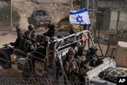 Israeli soldiers with the national flag stand on an armoured vehicle after crossing the security fence near the so-called Alpha Line that separates the Israeli-controlled Golan Heights from Syria, in the town of Majdal Shams, Dec. 12, 2024.