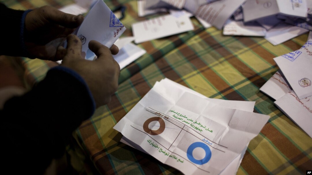 Petugas di TPS Mesir menghitung kertas suara dalam referendum terkait rancangan konstitusi baru yang kontroversial. (AP/Nasser Nasser)