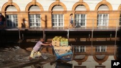 A man pushing a shopping cart loaded with bananas wade through a flooded street in downtown Manaus, Amazonas state, Brazil.