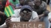 An opposition protestor holds a sign reading 'Faure, Resign,' referring to Togo's president, Faure Gnassingbe, and citing an article of the constitution that protesters say gives them the right to engage in civil disobedience, Aug. 25, 2012.