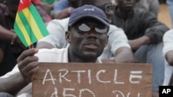 An opposition protestor holds a sign reading 'Faure, Resign,' referring to Togo's president, Faure Gnassingbe, and citing an article of the constitution that protesters say gives them the right to engage in civil disobedience, Aug. 25, 2012.