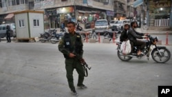 FILE - A member of the Kurdish internal security forces patrols a commercial street in Manbij, northern Syria, March 28, 2018. Manbij, a mixed Arab and Kurdish town of nearly 400,000, was freed from Islamic State militants in 2016 by YPG fighters with the backing of U.S. forces.