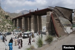 Warga setempat menunggu saat jalan ditutup setelah rel kereta api runtuh, sehari setelah militan separatis melakukan serangan mematikan, di distrik Bolan, provinsi Balochistan, Pakistan, 27 Agustus 2024. (Naseer Ahmed/REUTERS)