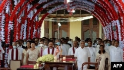 Preside Gotabaya Rajapaksa (depan,tiga dari kanan) dan PM Mahinda Rajapaksa (depan, tiga dari kiri) bersama para menteri kabinet baru menyanyikan lagu kebangsaan dalam upacara pelantikan kabinet di Kuil Buddha Gigi di ibukota bukit kuno Kandy, 116 km dari Kolombo,12 Agustus 2020.