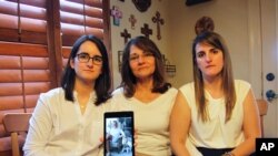 FILE - Dennysse Vadell sits between her daughters Veronica, right, and Cristina with a digital photograph of father and husband Tomeu, currently jailed in Venezuela, in Katy, Texas, Feb. 15, 2019. 