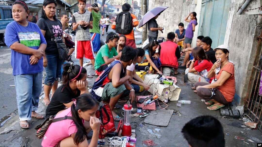 Các nạn nhân bão ở Tacloban vây quanh căn nhà có máy phát điện dự phòng để chờ sạc pin điện thoại di động