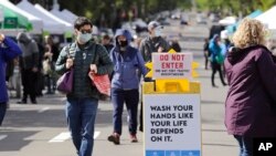 Masked customers walk through the West Seattle Farmers Market during its first opening in nearly two months because of the coronavirus outbreak Sunday, May 3, 2020, in Seattle. 