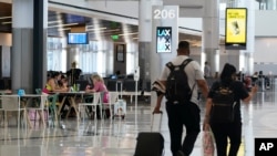 Penumpang menunggu jadwal penerbangan mereka di dalam Gerbang Barat di Terminal Internasional Tom Bradley, Bandara Internasional Los Angeles, pada 24 Mei 2021. (Foto: AP/Ashley Landis)