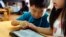 FILE - Children work on a digital program at Coby Preschool in Yoshikawa, suburban Tokyo, on an assignment, which was to draw on a triangle on an iPad, July 12, 2018.
