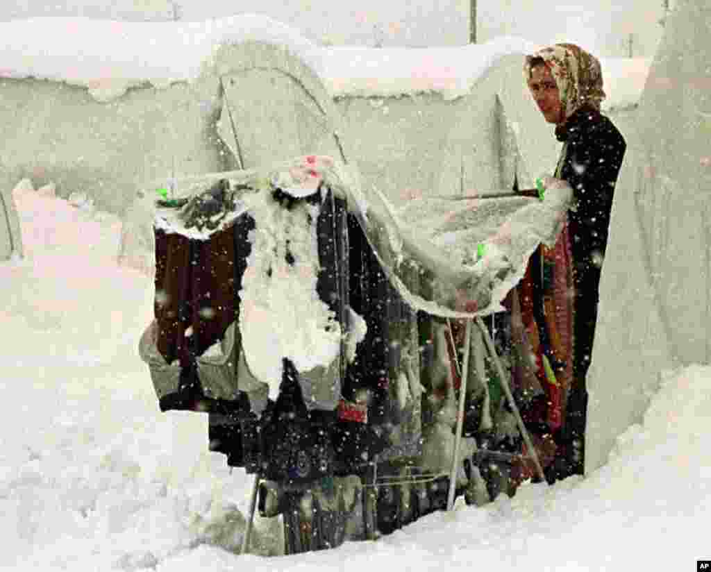 An earthquake victim stands next to the clothes hung to dry as snow falls at a tent city near the northwest Turkish town of Duzce, January 26, 1999. (Reuters)