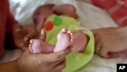 In this Nov. 5, 2015 photo, a couple from Britain whose baby was born on Oct. 17 by a surrogate pose their baby for a photo in Anand, India. For 15 years the couple were unable to get pregnant and turned to Dr Nayna Patel's clinic after seeing her on a TV program. (AP Photo/Allison Joyce)