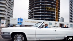 In this Jan. 17, 2017 photo, a man drives a convertible past a Trump Tower under construction in Punta del Este, Uruguay.