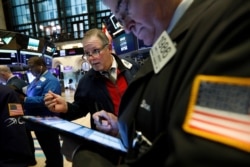 Michael Conlon, center, works with fellow traders on the floor of the New York Stock Exchange, March 12, 2020.