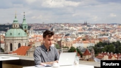 FILE - Joseph Petrila, a 23-year-old job seeker, uses a laptop in a cafe near the Prague Castle following the coronavirus outbreak, in Prague, Czech Republic, July 8, 2020. 