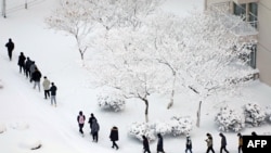 Orang-orang berjalan di jalur yang tertutup salju di Yantai, provinsi Shandong China timur, 7 Januari 2021, setelah otoritas meteorologi China mengeluarkan peringatan cuaca buruk di sebagian besar negara itu. (Foto oleh STR / AFP)
